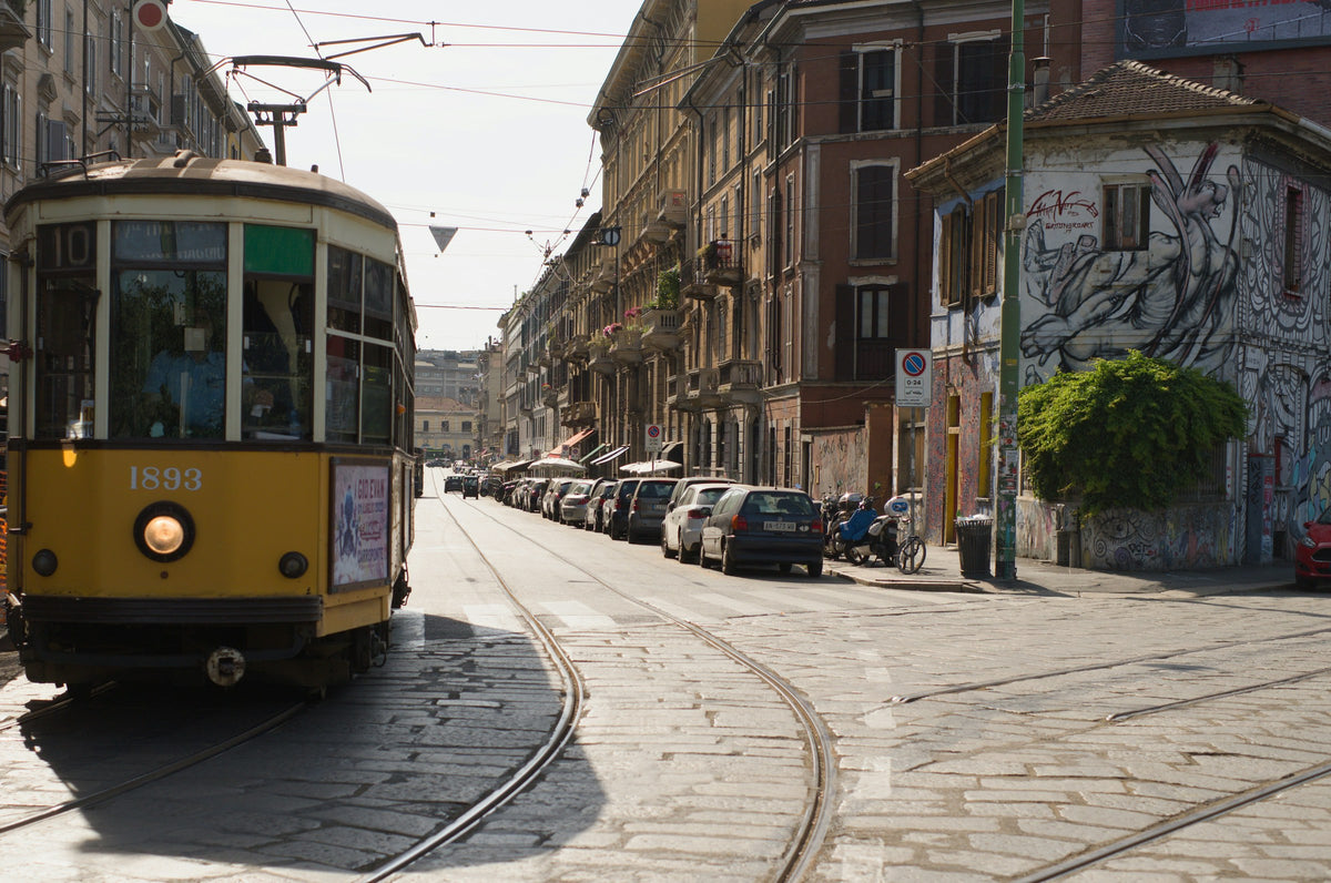 A vintage yellow tram on cobbled tracks in Milan