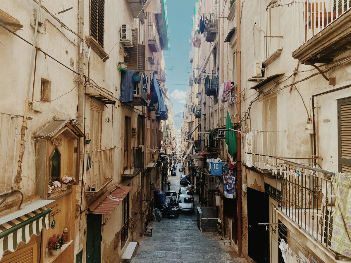 A narrow Naples alley with laundry and a shrine