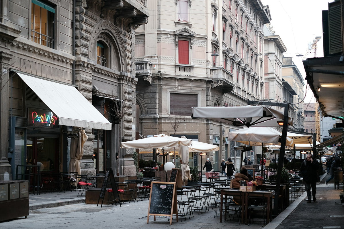 A busy shopping street with outdoor tables and umbrellas
