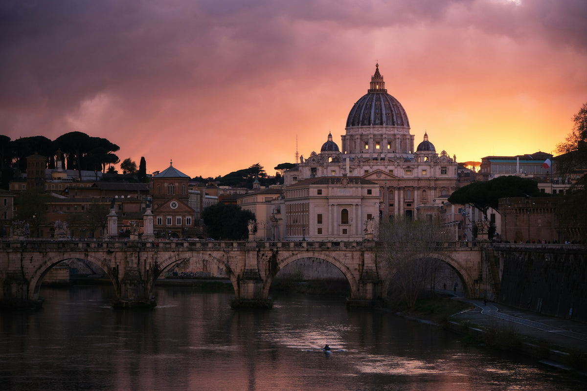 The dome of St Peter's rising beyond the Tiber at sunset