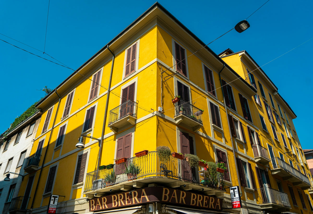 A yellow building with balconies above Bar Brera