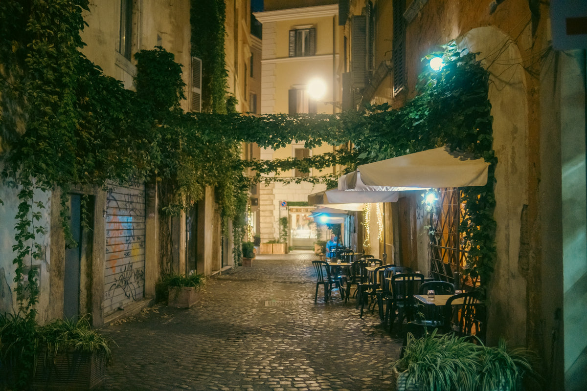 Outdoor tables on an ivy-hung cobbled lane in Trastevere at night