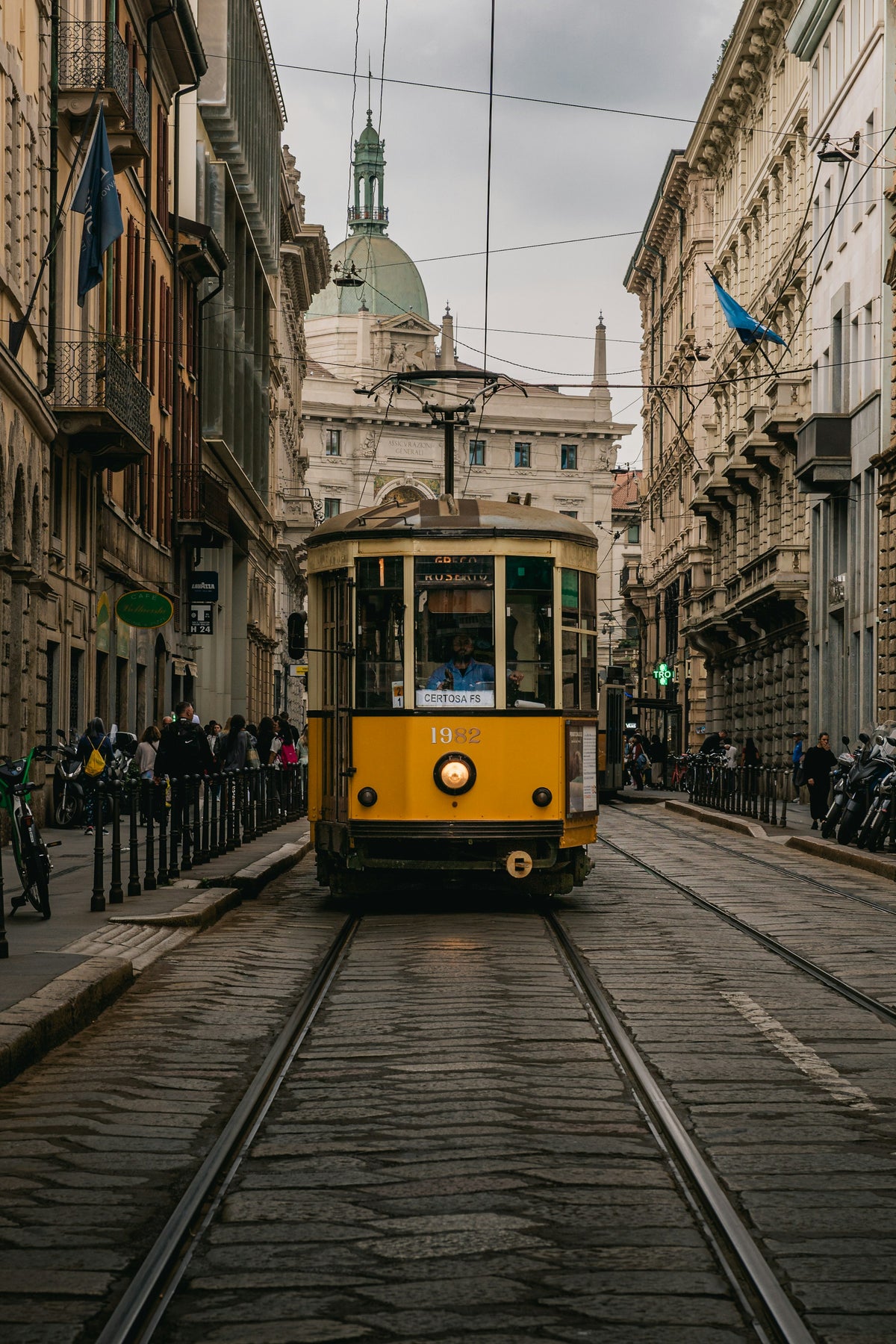 A vintage yellow tram running between Milan buildings