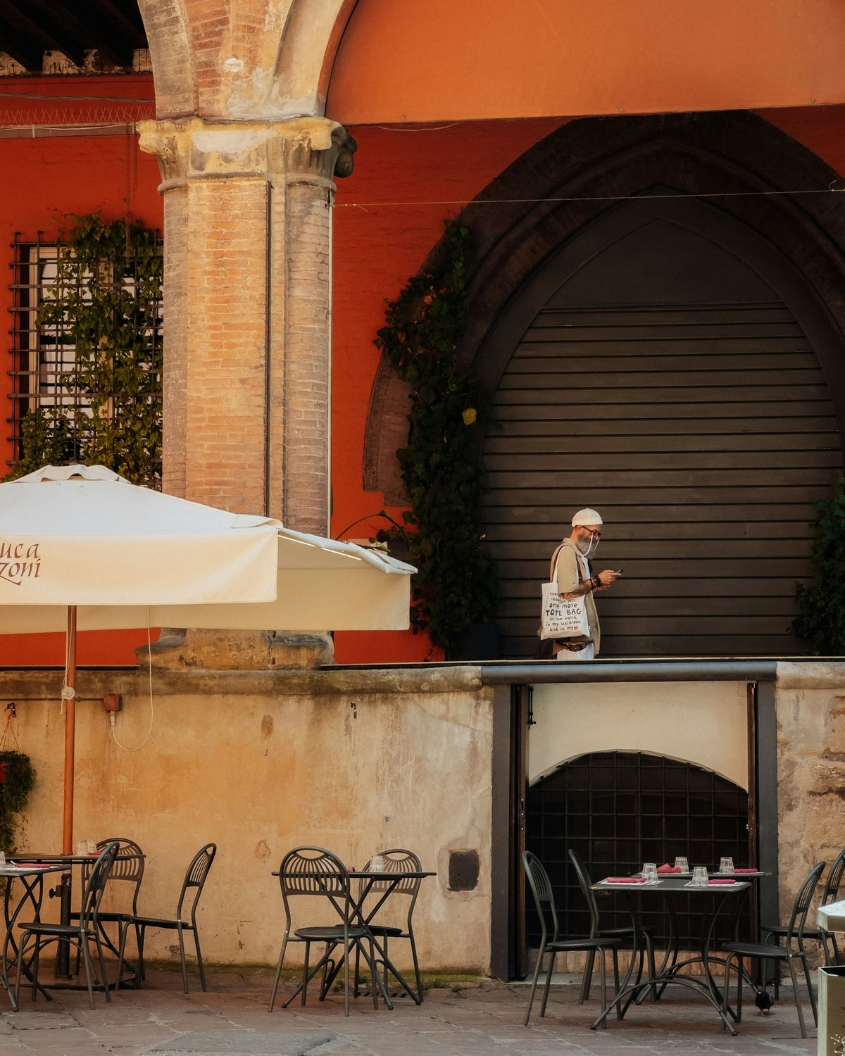 A man with an umbrella outside a restaurant in Bologna