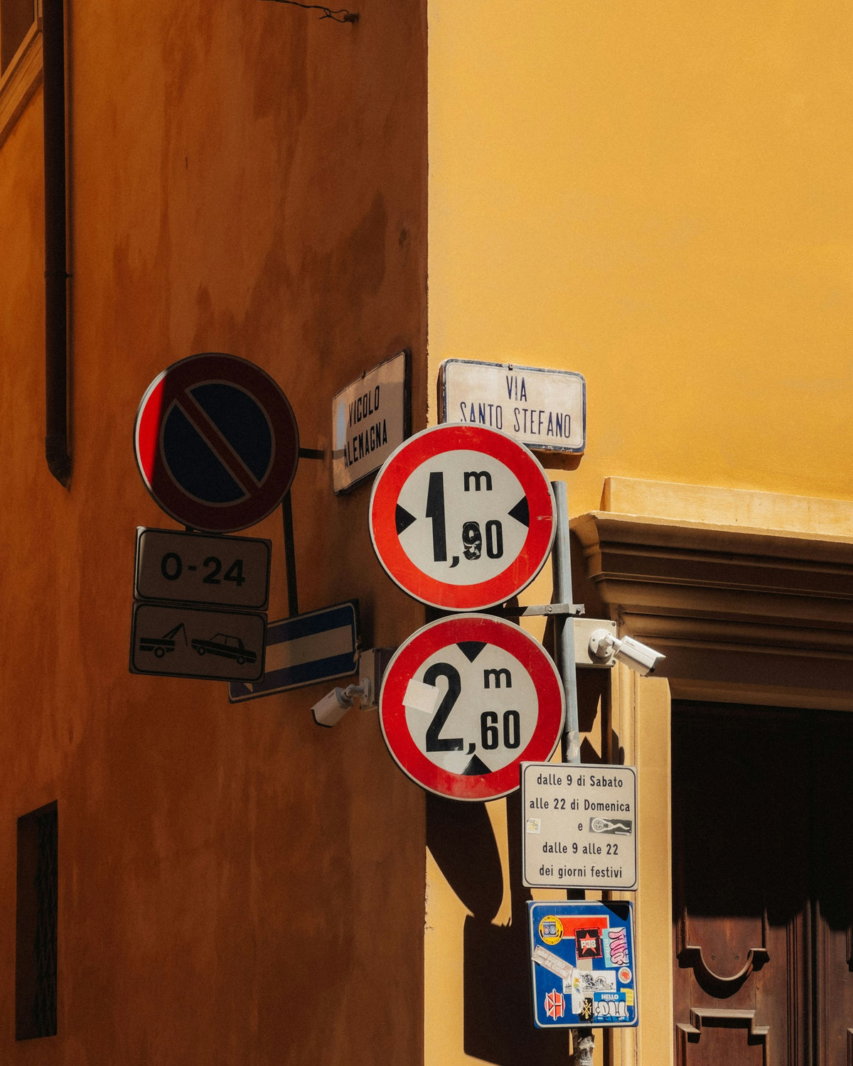 A cluster of street signs on a building in Bologna