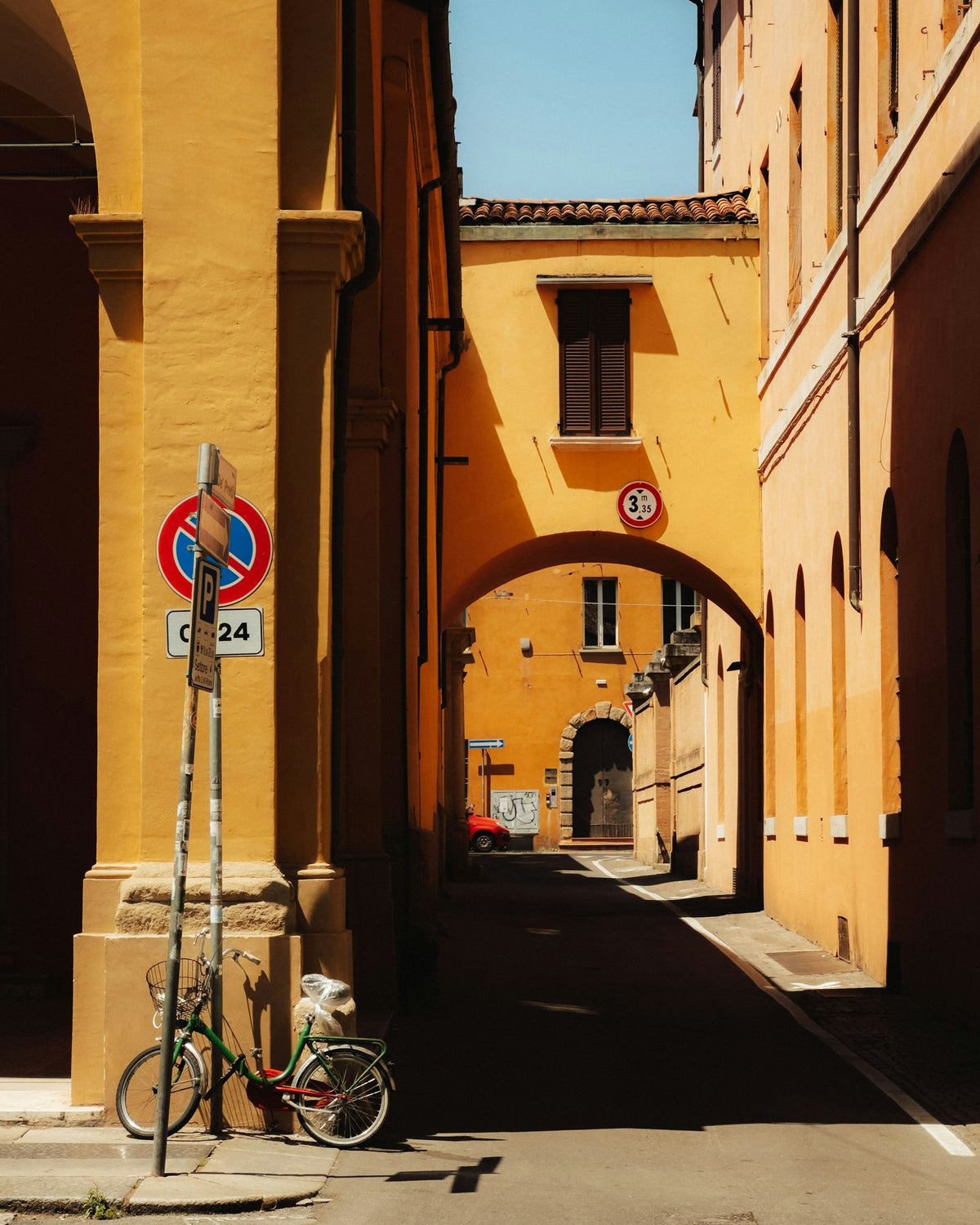 A bike parked on a Bologna street, with hard light casting shadows on the walls