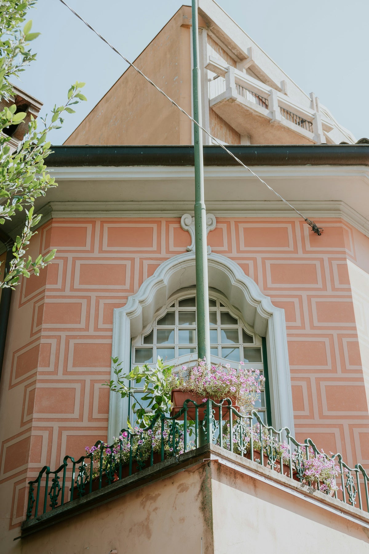 A pink facade and its flower-filled balcony