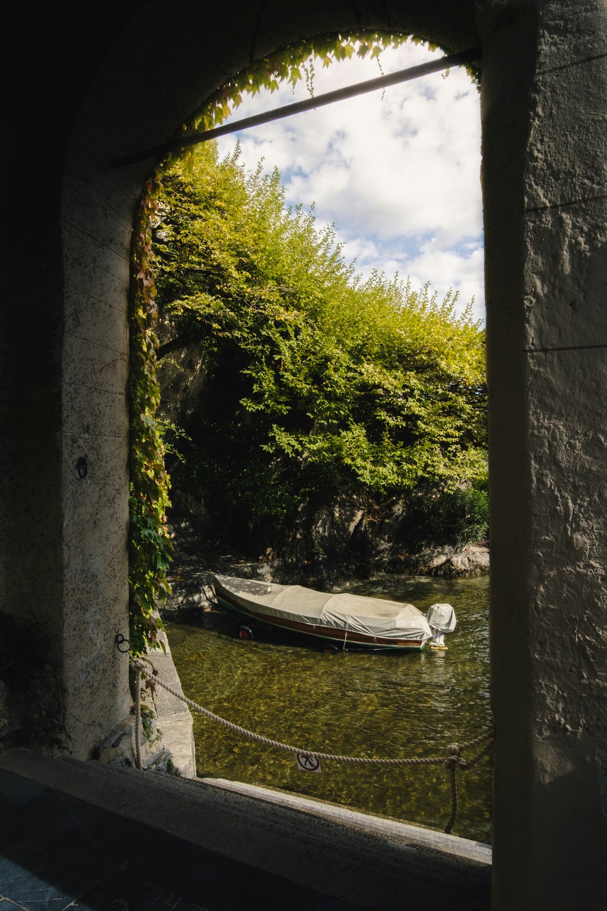 A boat on the lake seen through an archway at Villa del Balbianello