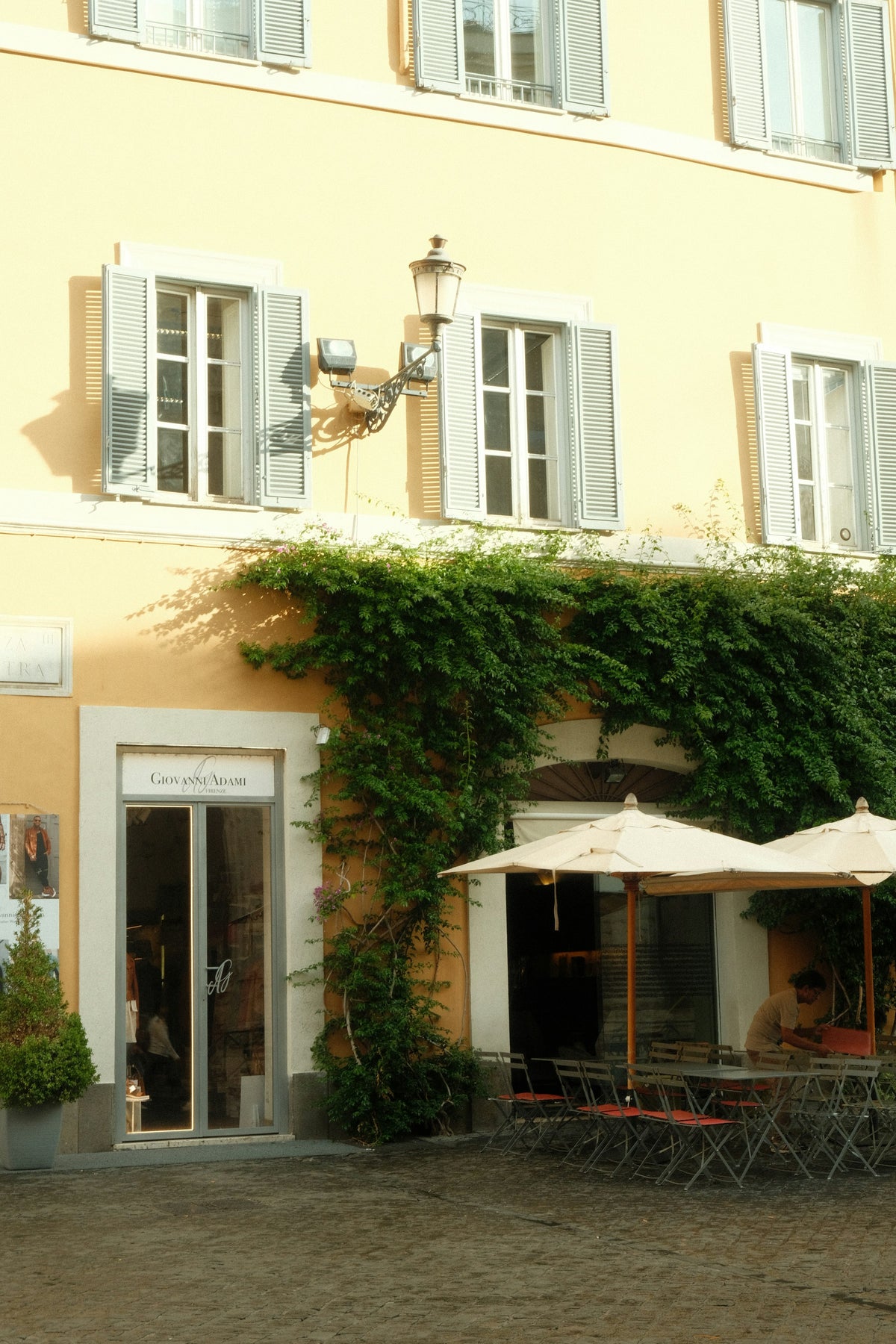 A café beneath an ivy-covered yellow building