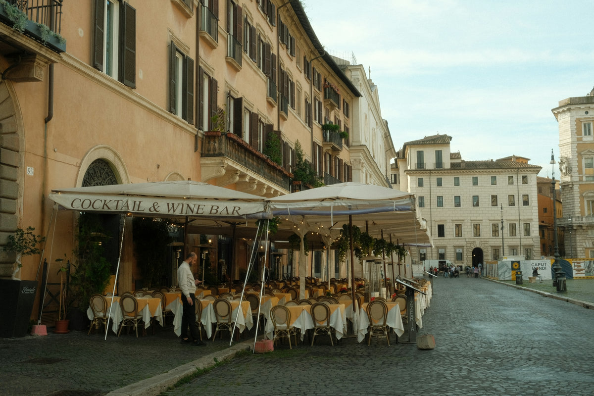 Restaurant terraces under white umbrellas in a Roman piazza