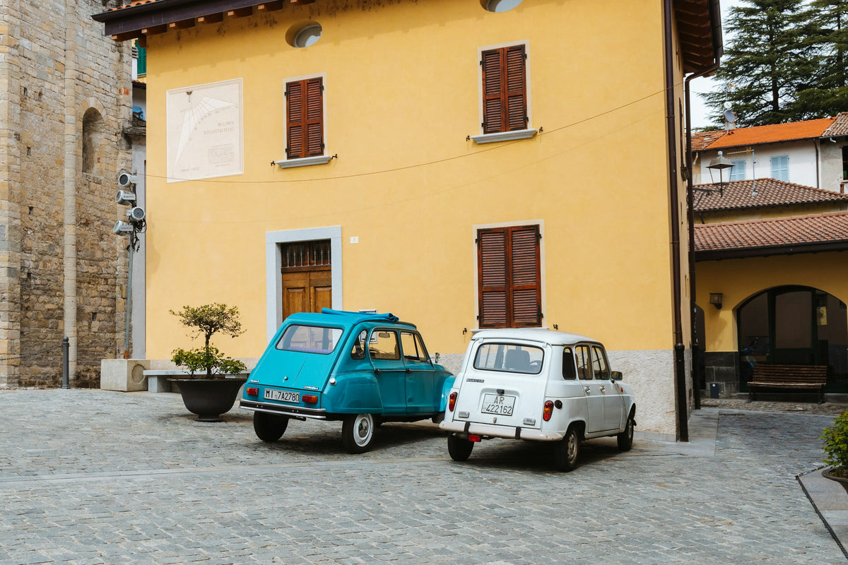 Two vintage cars outside a yellow house