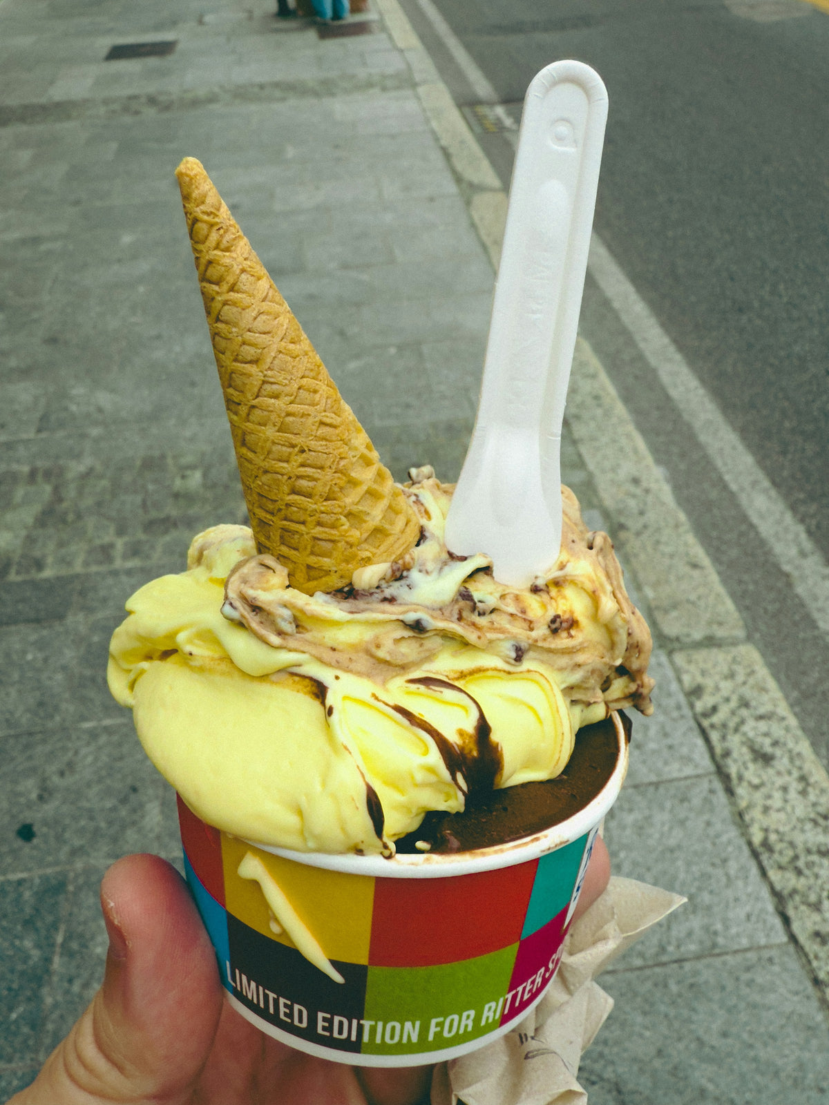 Saffron and chocolate gelato topped with a cone, on a Milan street