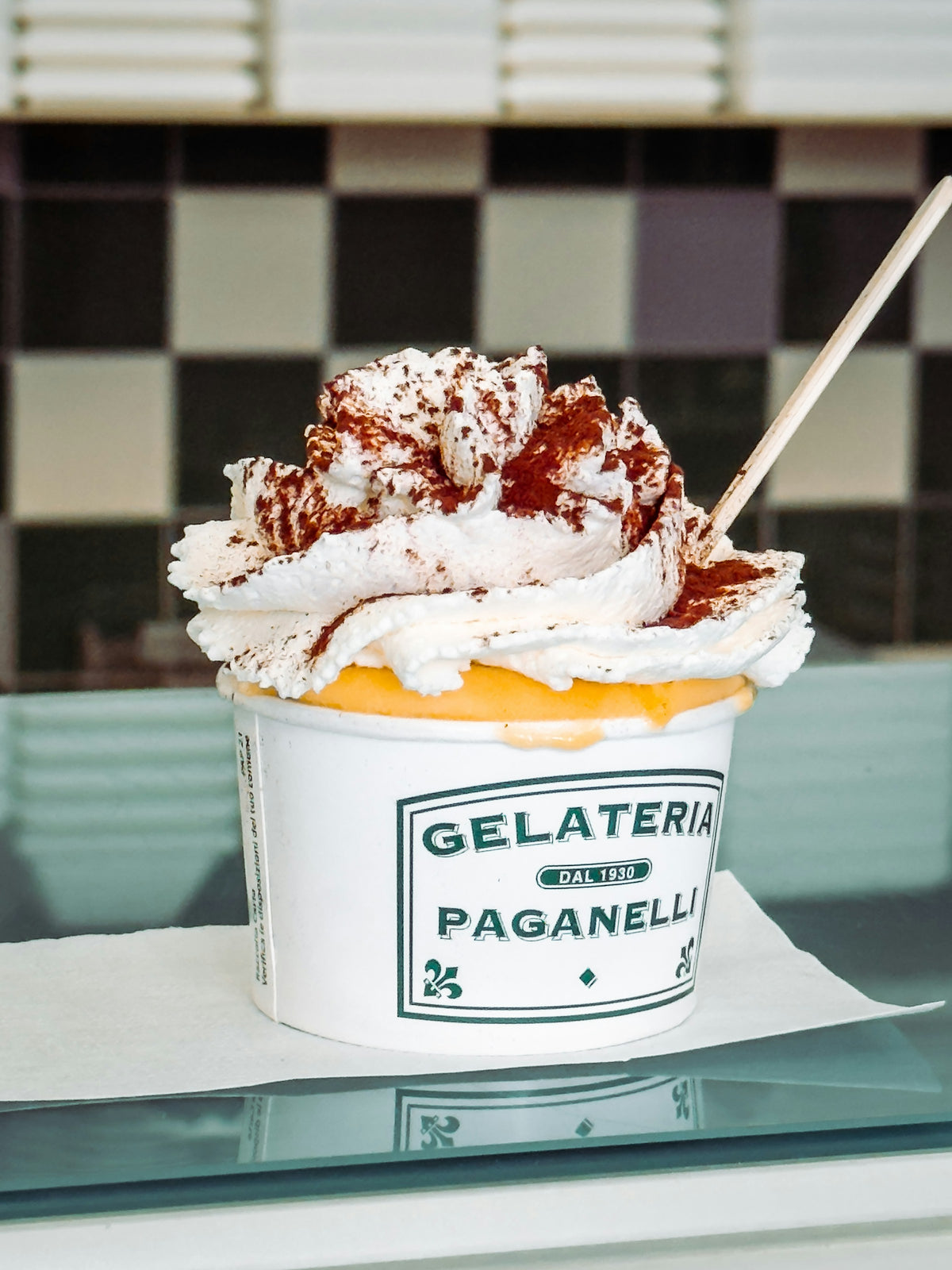 A gelato cup with whipped cream and cocoa from a Milan gelateria