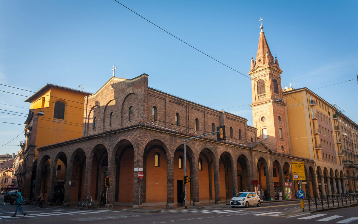 A brick church with a tall bell tower and arched portico under a clear sky