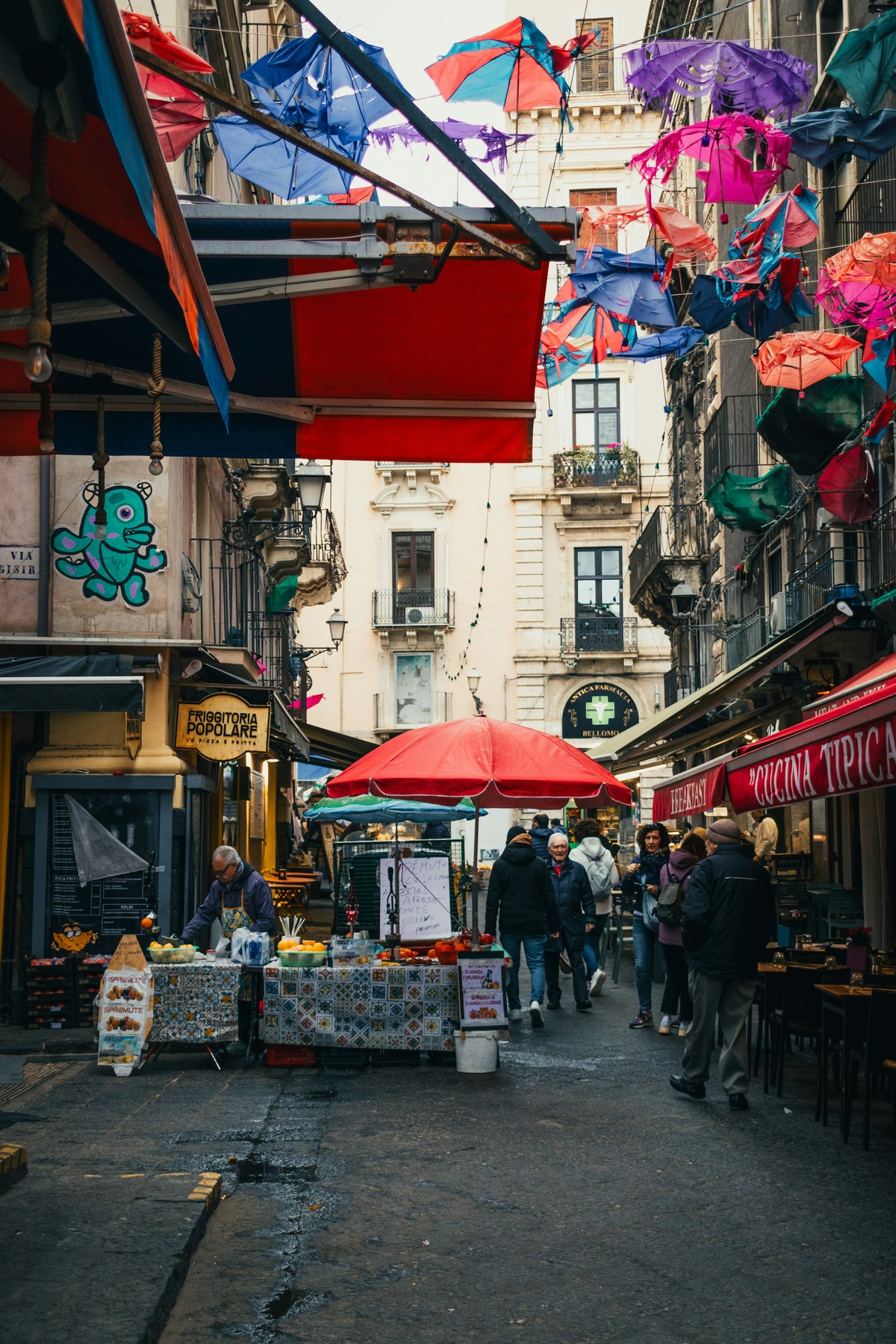 Shoppers and stalls under floating umbrellas