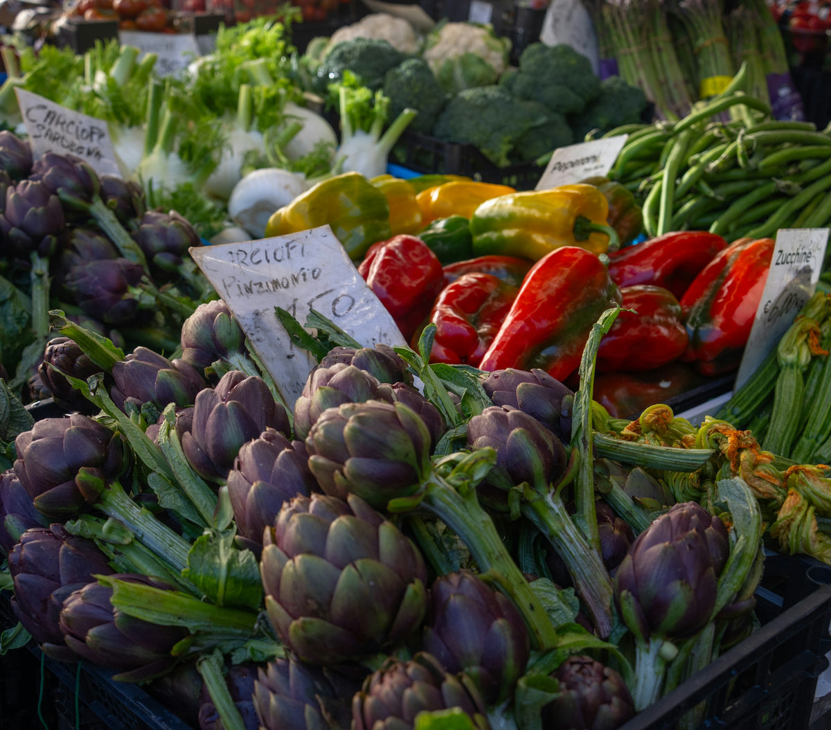 Artichokes and peppers piled high on a market stall