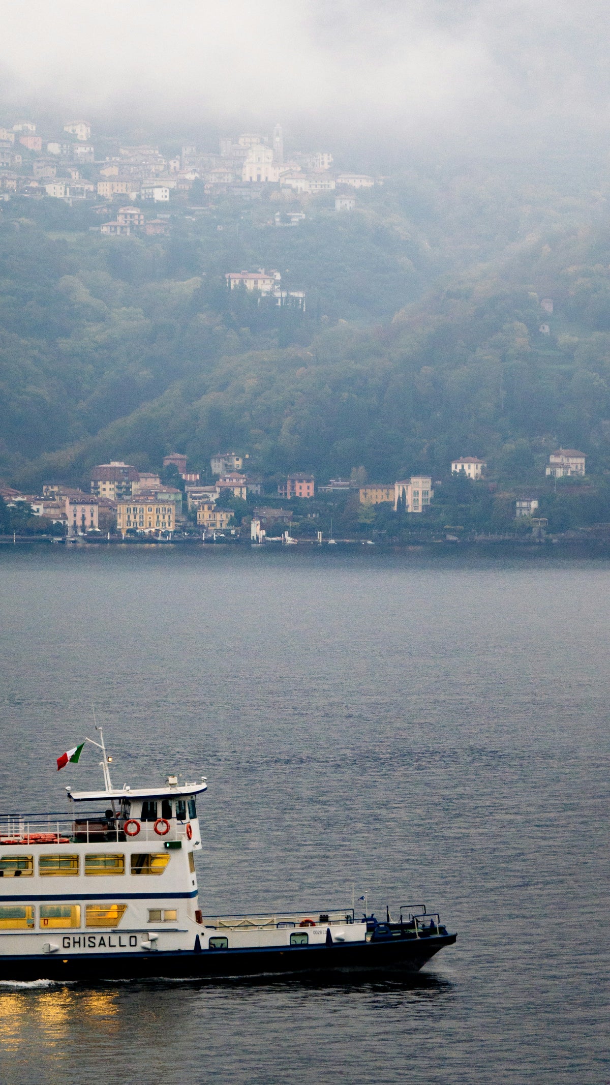 A ferry on the lake at Menaggio below a misty hillside