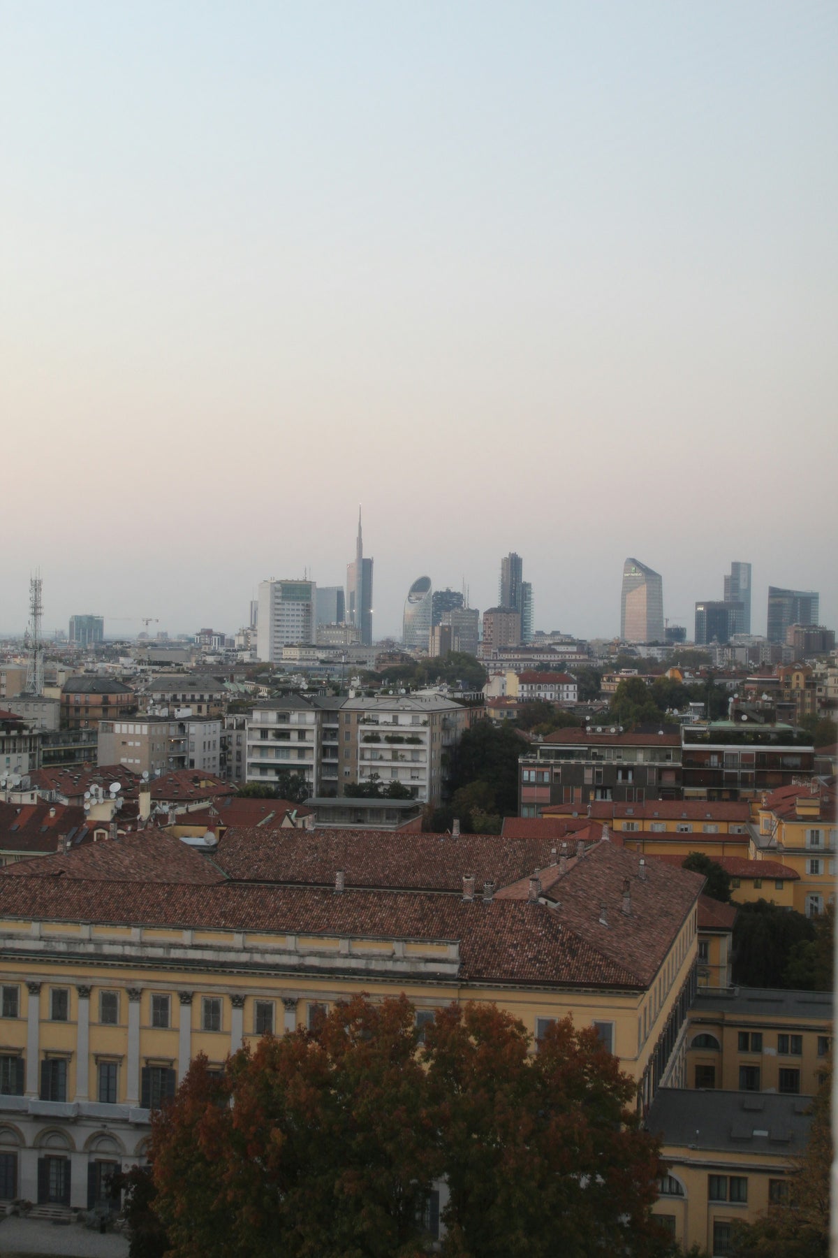 Milan's skyline of modern towers and traditional rooftops at dusk
