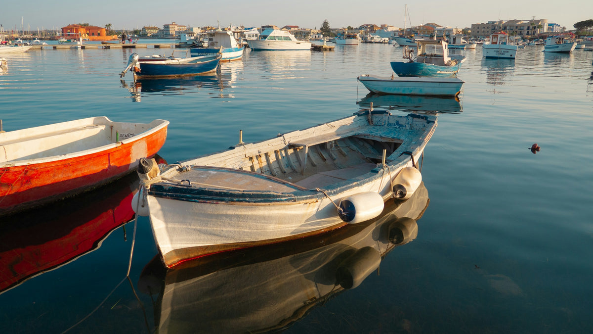 Wooden boats in the calm harbour of Aci Castello
