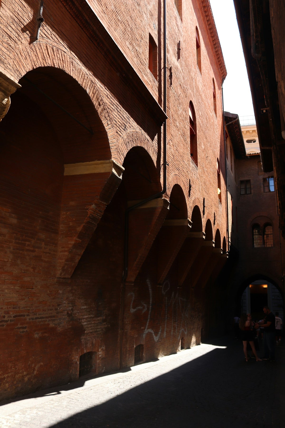 Red brick porticoes in a narrow, sun-and-shadow street