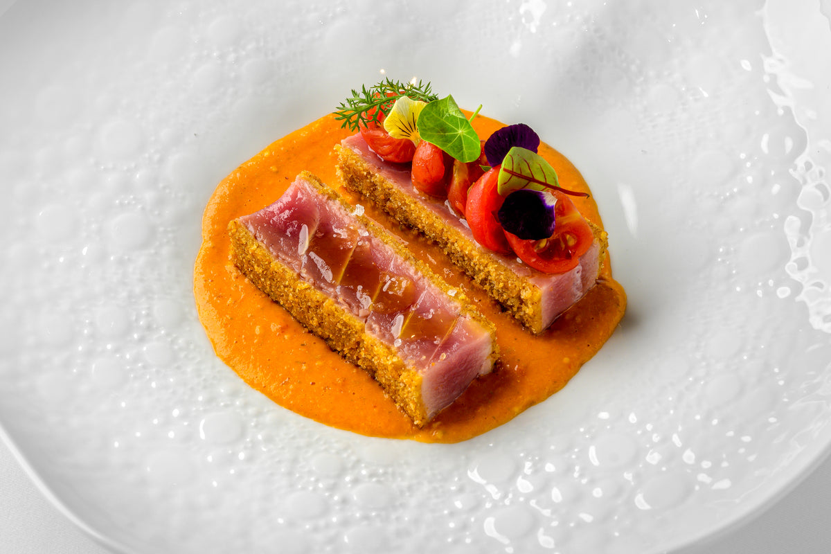 Seared tuna with crisp crust on an orange sauce, garnished with microgreens and edible flowers, at Acqua Restaurant