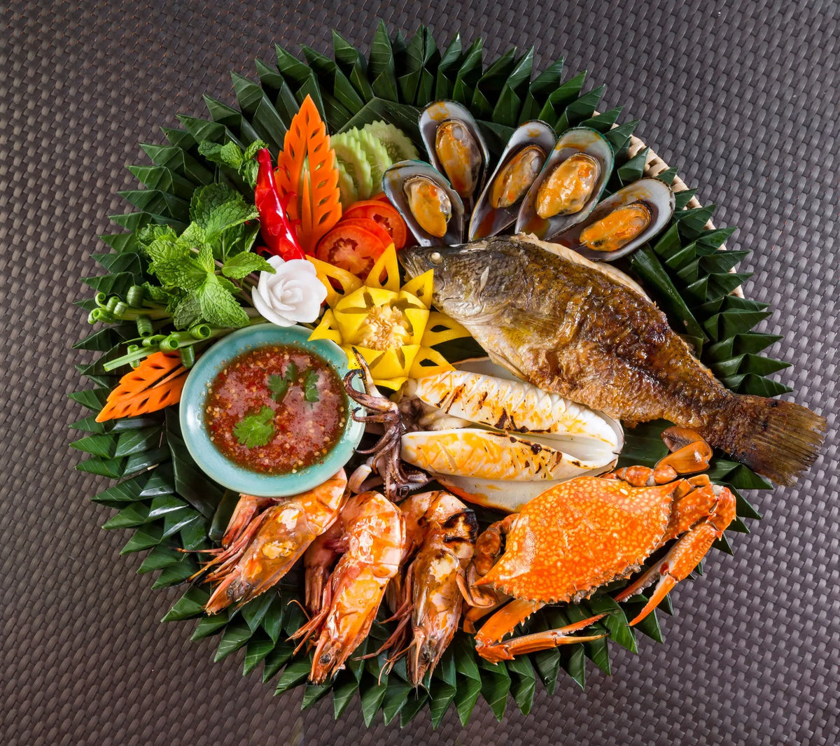 Thai seafood platter with grilled fish, prawns, crab and mussels on banana leaves at Baan Rim Pa