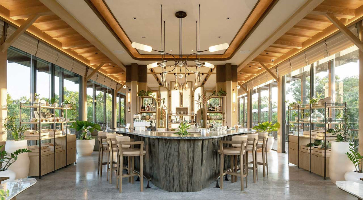 Central bar under a pendant chandelier with garden views at JAMPA