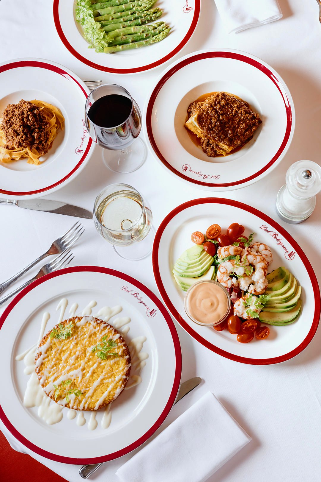 A spread of dishes on red-rimmed plates at Dal Bolognese