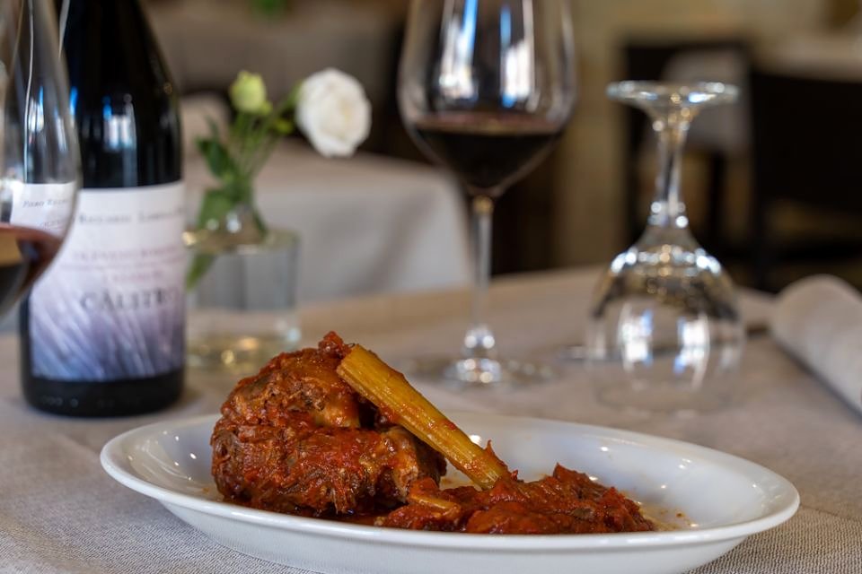 A slow-cooked meat dish and a glass of red at La Tavernaccia Da Bruno