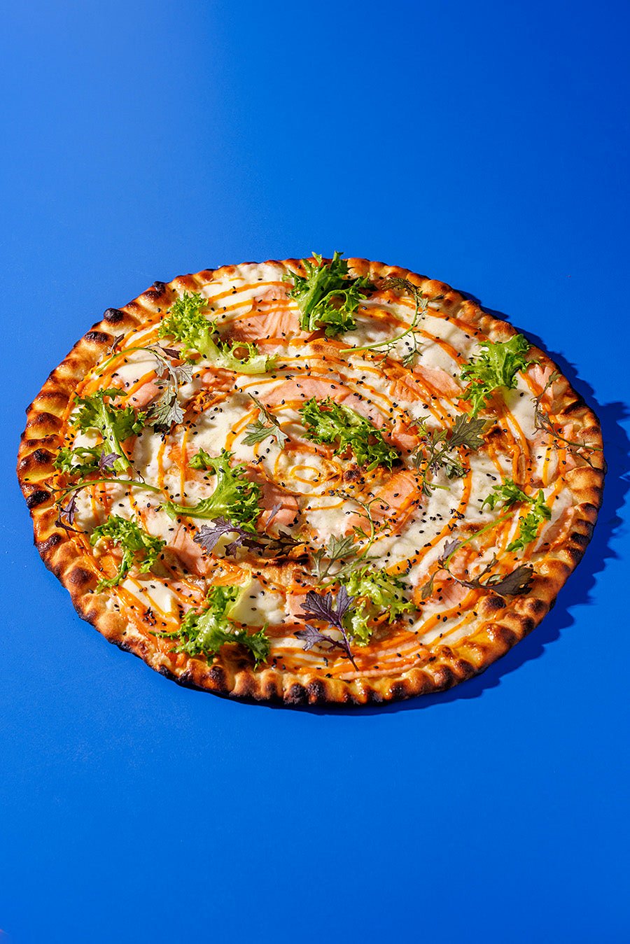 A whole pizza scattered with herbs at Seu Pizza Illuminati