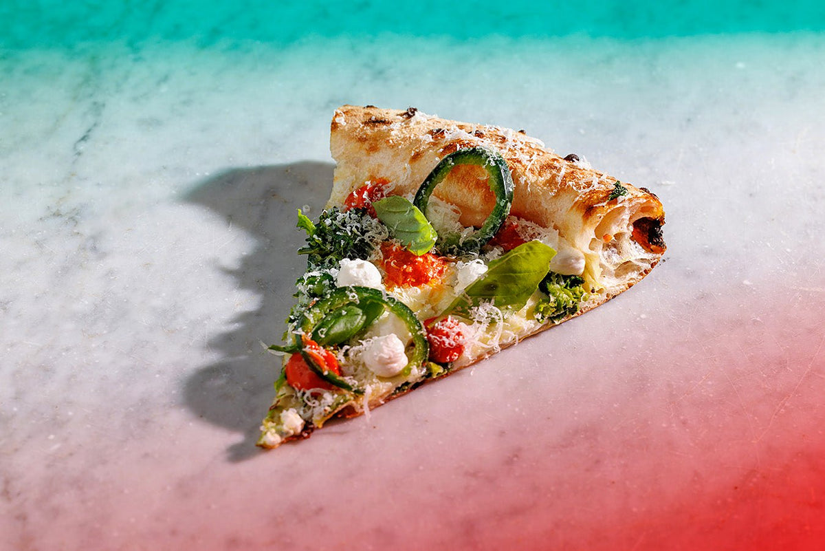 A slice topped with fresh vegetables at Seu Pizza Illuminati