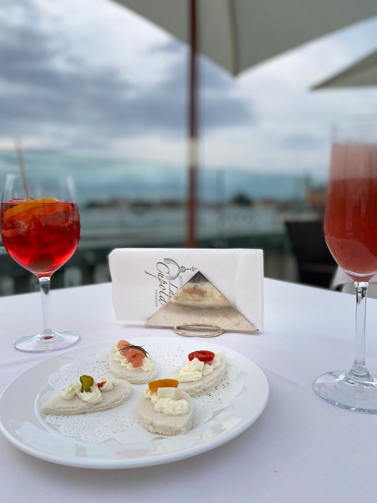 Canapés and two spritz-style drinks on a terrace overlooking the lagoon