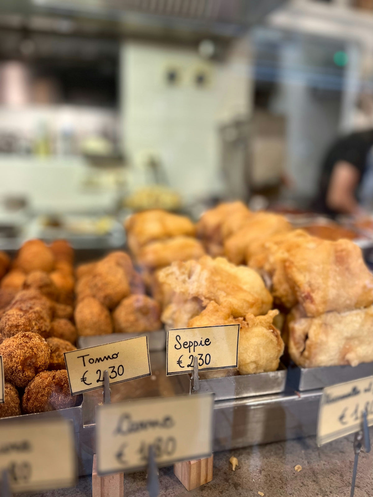 Fried cicchetti labelled tonno and seppie in a Venice bar display