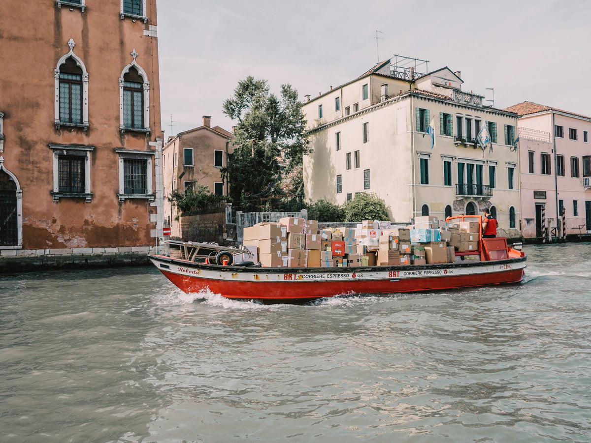 A courier boat loaded with parcels crossing a Venice canal