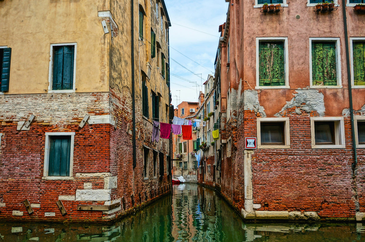 Weathered brick houses and hanging laundry above a quiet side canal