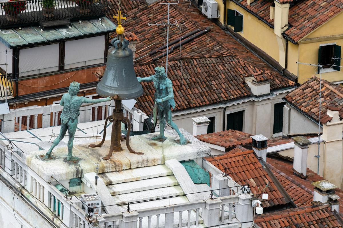 Bronze Moors and bell on top of the Clock Tower above Venetian rooftops