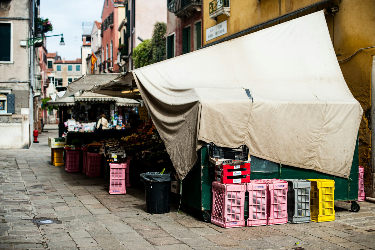 A fruit and vegetable stall with stacked crates in a Venetian street