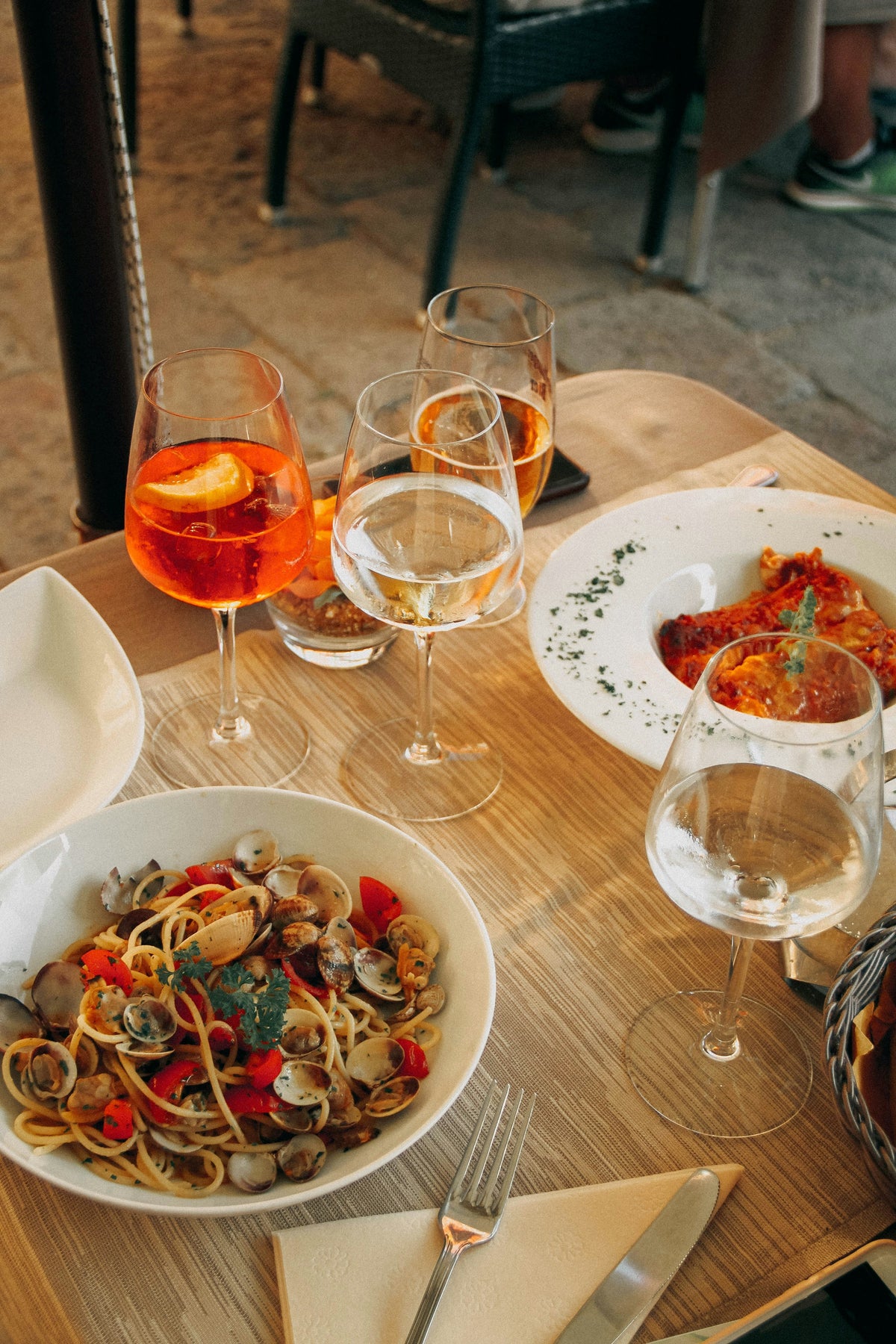 Spaghetti with clams, spritz and white wine on an outdoor table