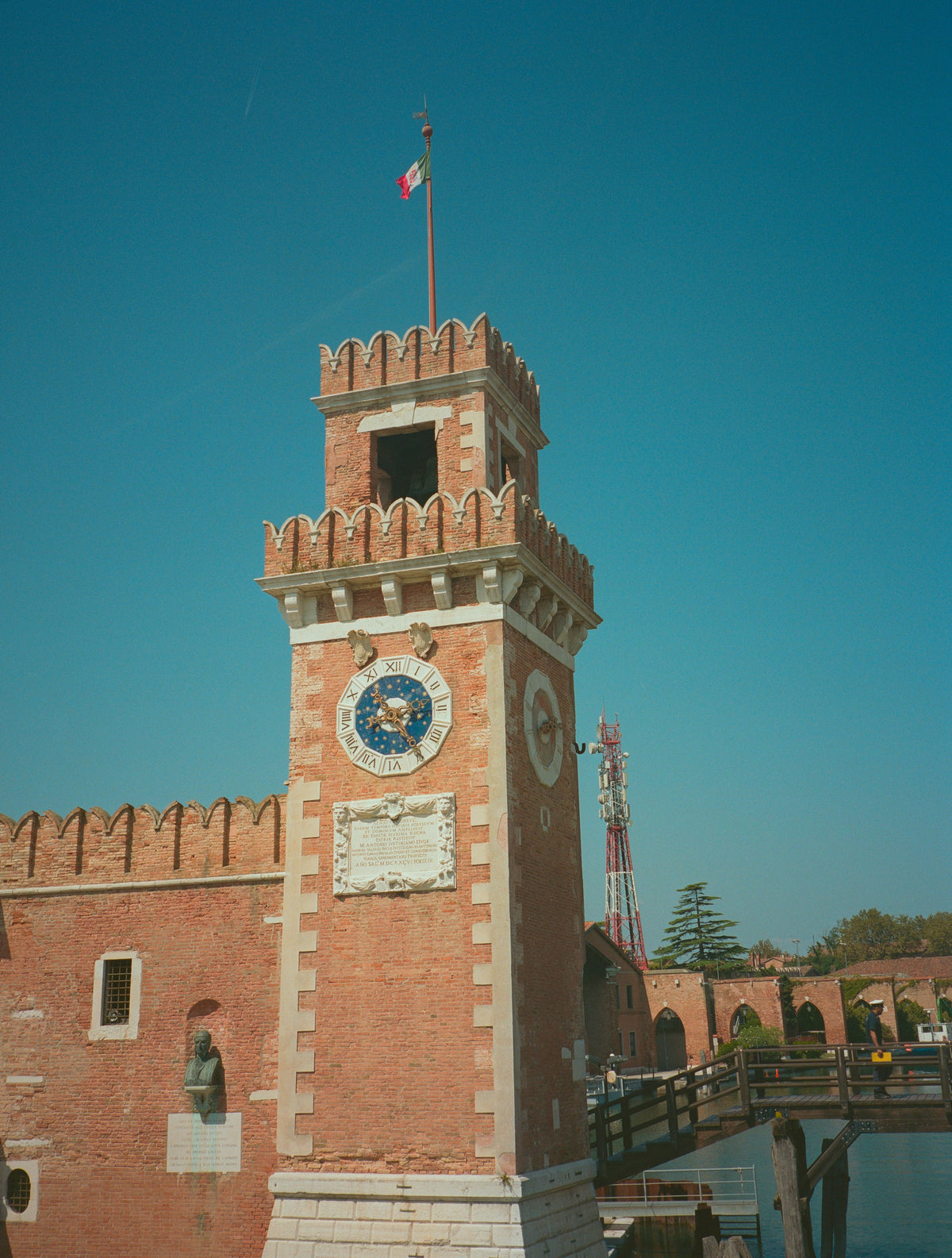 Crenellated clock tower at the Arsenale under a clear blue sky