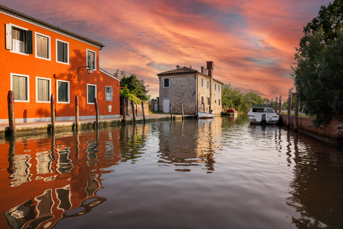 A canal on Torcello at sunset, with houses reflected in the water