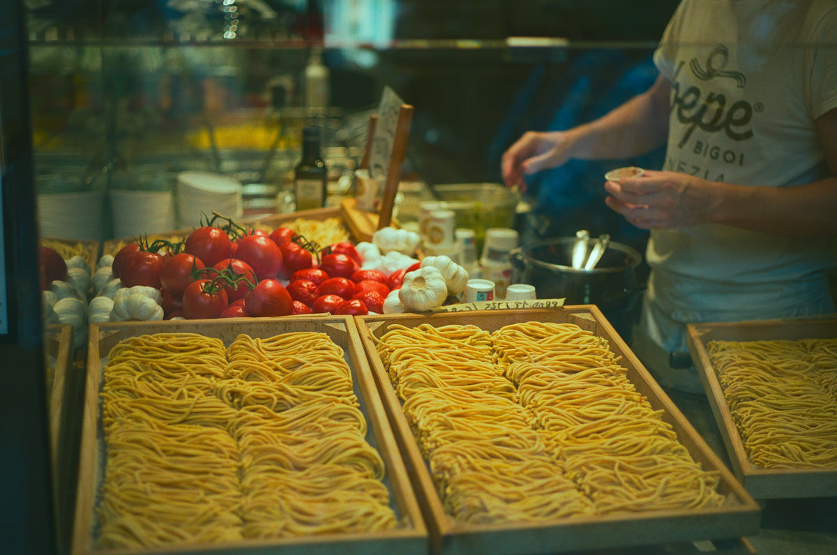 Trays of fresh bigoli pasta with tomatoes and garlic in a Venice shop
