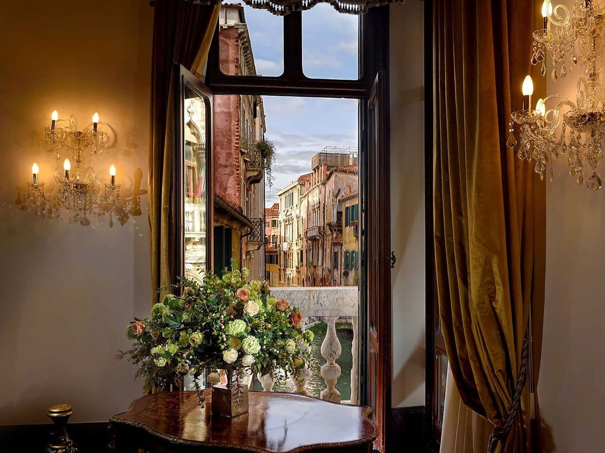 Royal Suite window with flowers and candle sconces, opening onto a Venetian canal