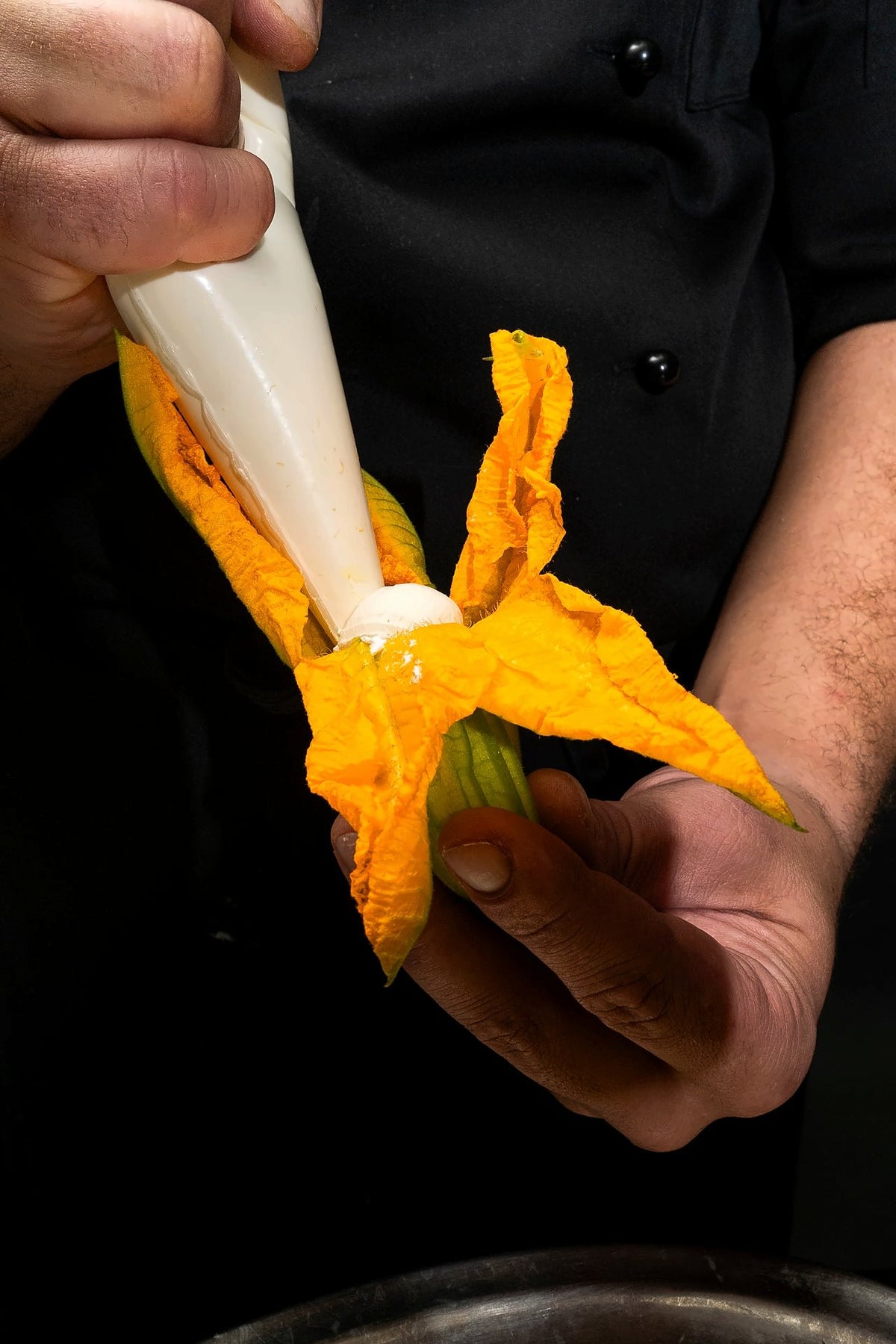 Chef piping a filling into a courgette flower at Ai Mercanti