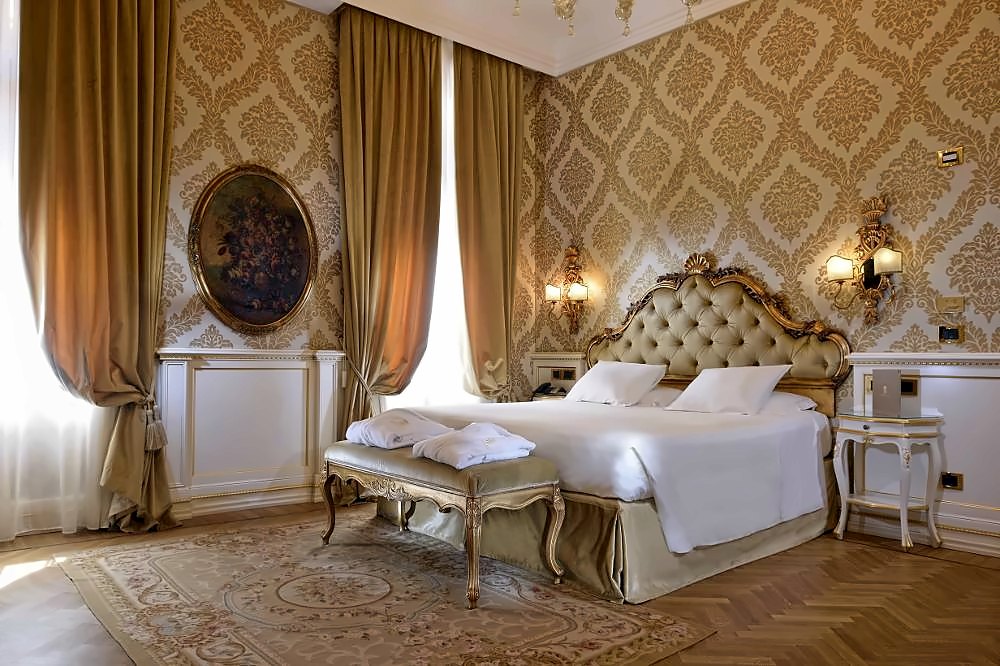 Venetian bedroom with damask walls, gilded headboard and silk curtains