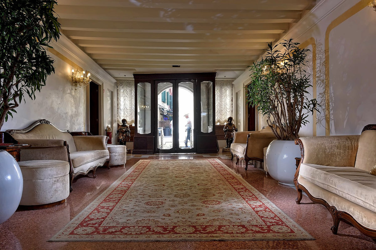 Long lounge hall with Persian rug, cream sofas and glazed doors at the far end