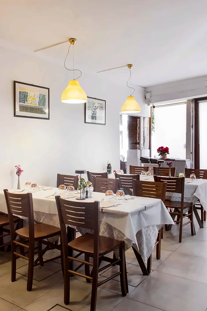 Bright dining room with white tablecloths and yellow pendant lamps