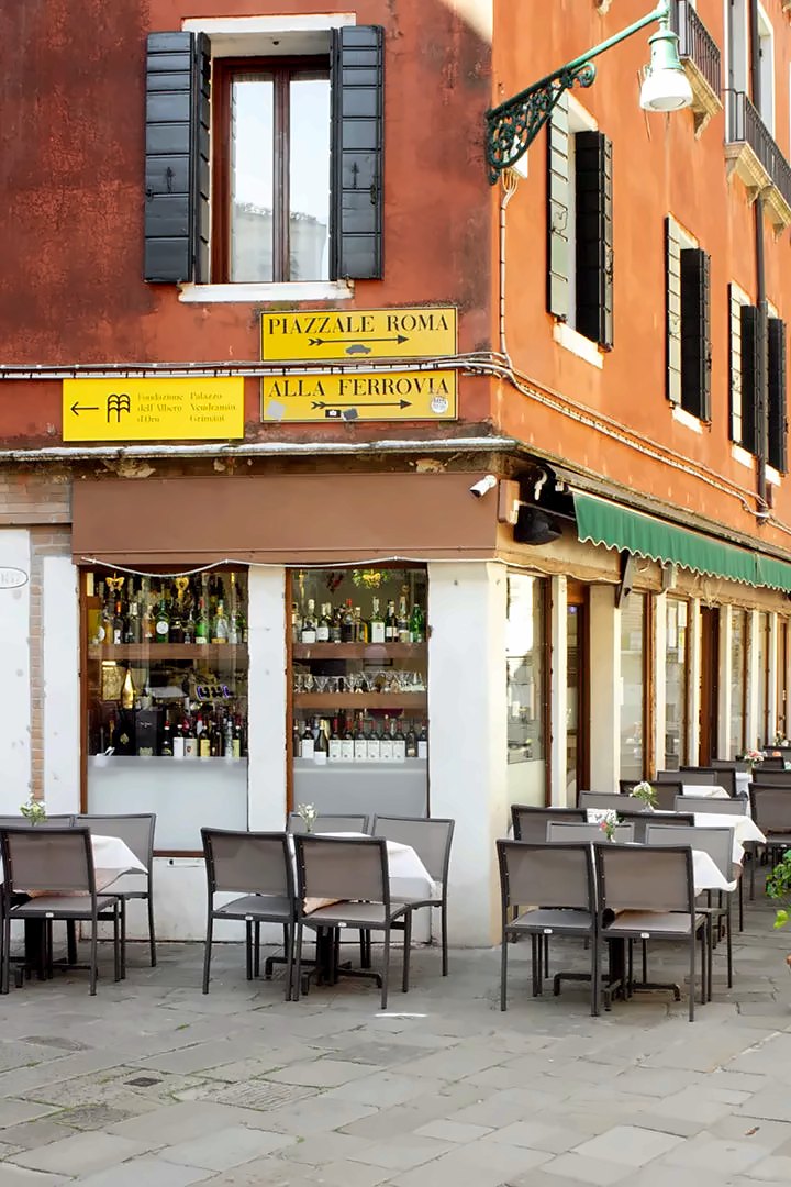 Corner exterior with outdoor tables and a wine-filled shop window