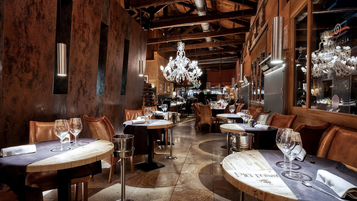 Long dining room with Murano chandeliers, leather chairs and laid tables