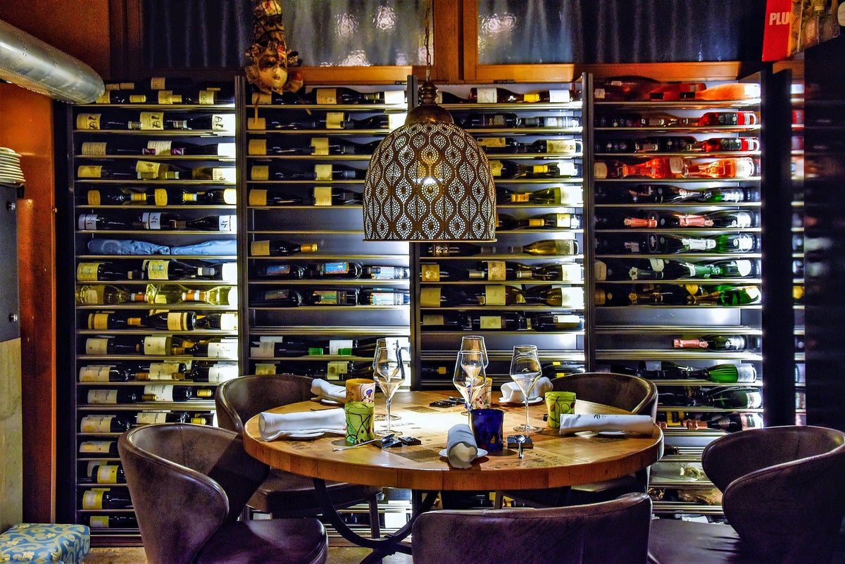 Round table set in front of a backlit wall of wine bottles