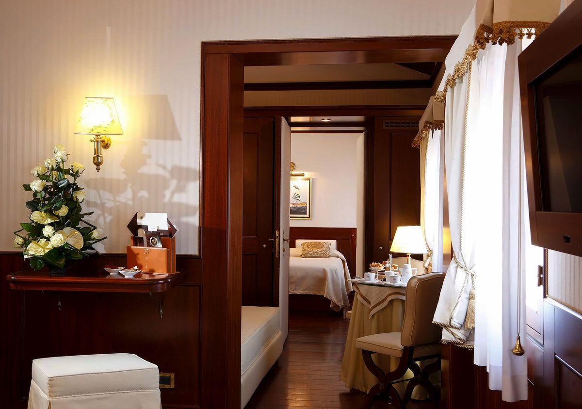 Wood-panelled suite with flowers and a small table, the bedroom beyond